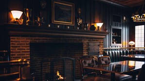 Una habitación acogedora con chimenea de ladrillo, asientos de cuero y una mesa.