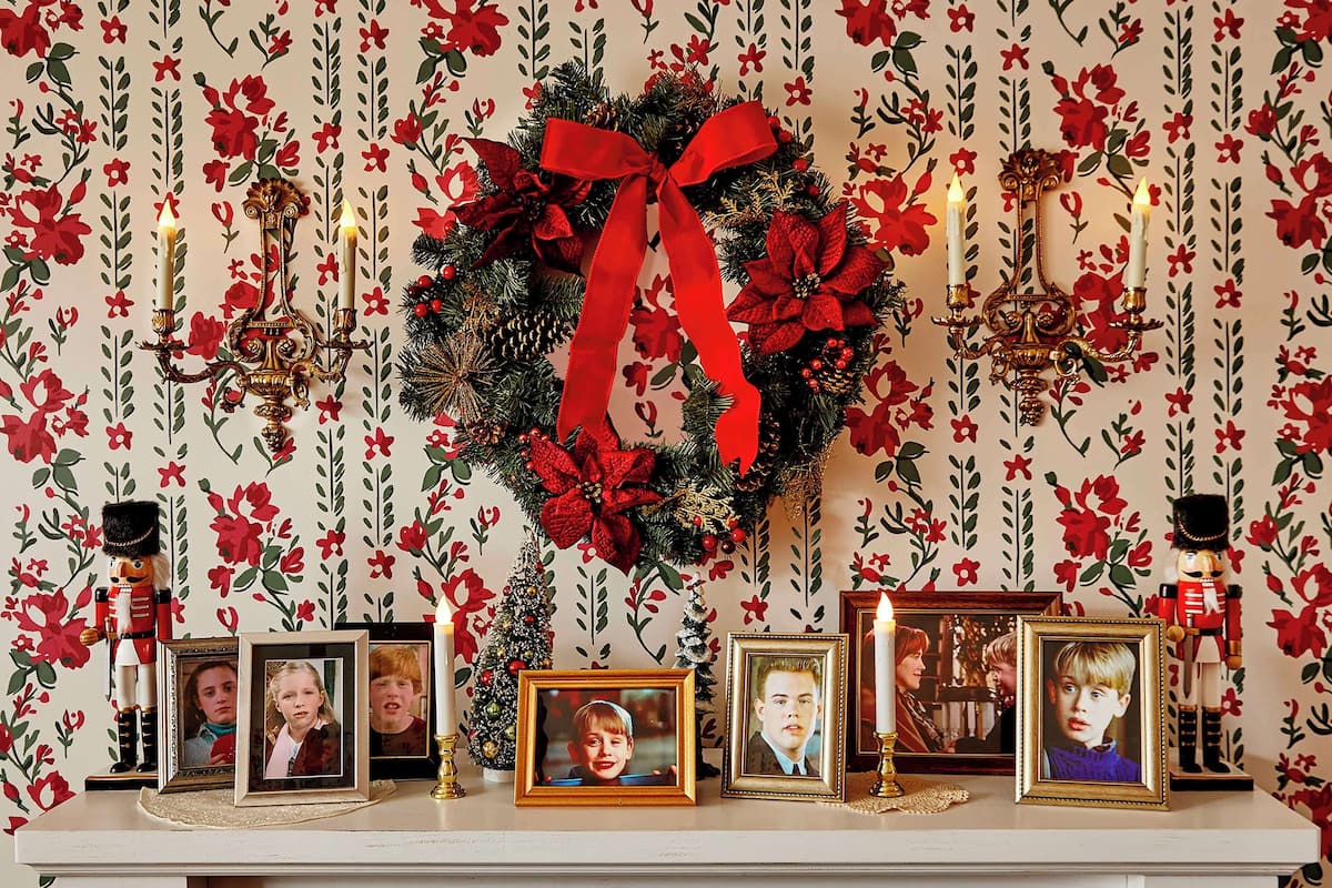 Una repisa con marcos de fotos, un adorno navideño y velas.
