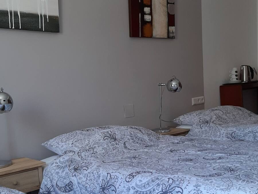 Un dormitorio con una cama grande, una mesita de noche, una lámpara, una obra de arte en la pared y un armario pequeño.