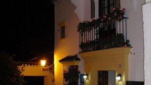 A building with a balcony with flowers, a door, and a light fixture. - Hotel Ronda (Ronda)