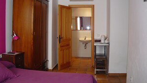 A bedroom with a bed, a wardrobe, a bedside lamp, and a bathroom with a sink and mirror. - Hotel Ronda (Ronda)