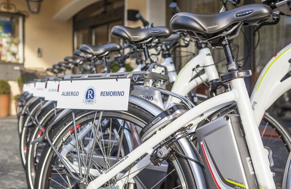 A row of bicycles parked in front of a building with signs indicating rental locations.