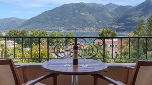 A balcony with a table and chairs, overlooking a mountainous landscape and a lake. - Boutique-Hotel REMORINO (Minusio)