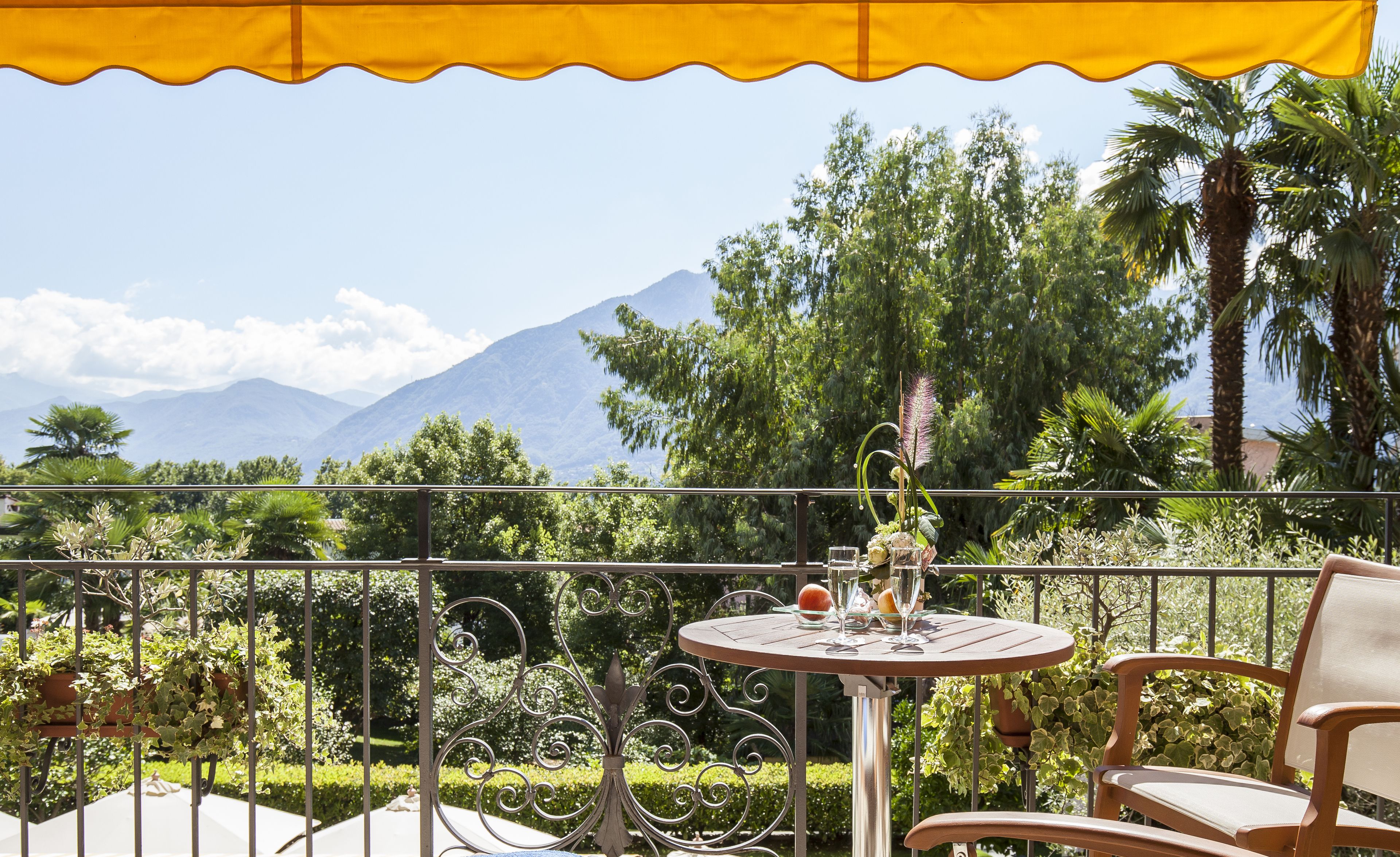 Un balcón con mesa y silla, con vista a un paisaje montañoso.