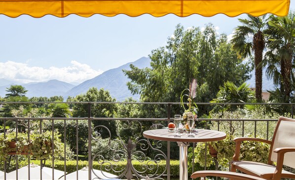 A balcony with a table and chair, overlooking a mountainous landscape.
