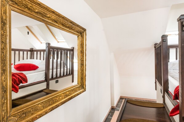 Un dormitorio con cama de madera, un espejo grande y decorativo, y un tragaluz.