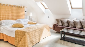 A bedroom with a large bed, a sofa, and skylights. - Hotel Leon D´Oro (Prague)