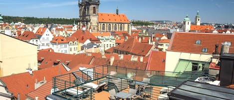 A rooftop terrace with outdoor seating and a view of historic buildings and a church.