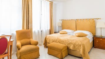 A hotel room with a bed, a chair, a nightstand, and a lamp.