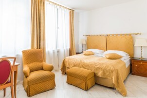 A hotel room with a bed, a chair, a nightstand, and a lamp.