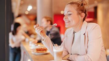 A person dining at a restaurant with a table, a drink, and a spoon.