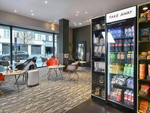 A hotel lobby with seating, a beverage refrigerator, and a view of the street. - ibis Kortrijk Centrum (Kortrijk)