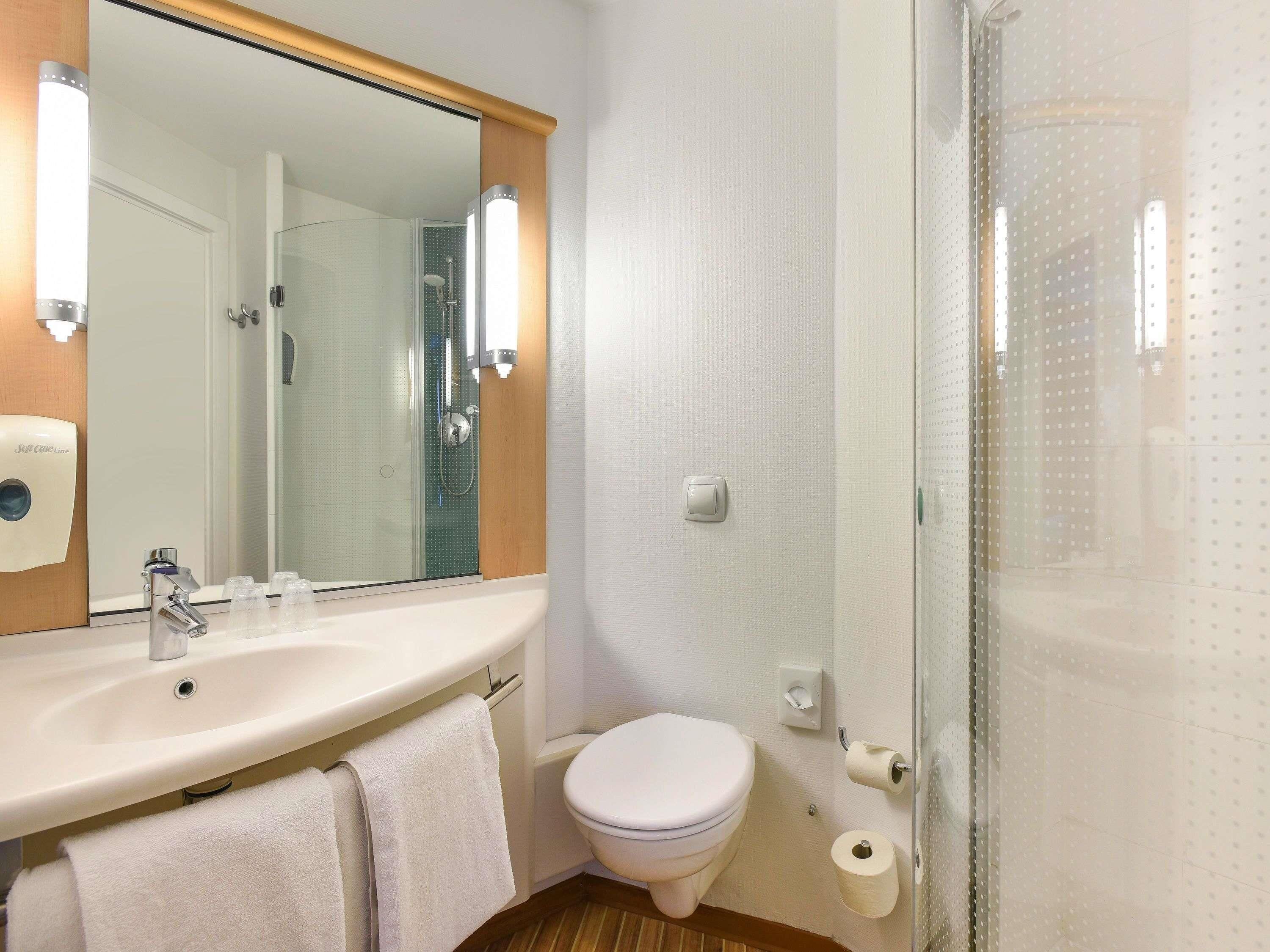 A bathroom with a sink, mirror, toilet, and shower.