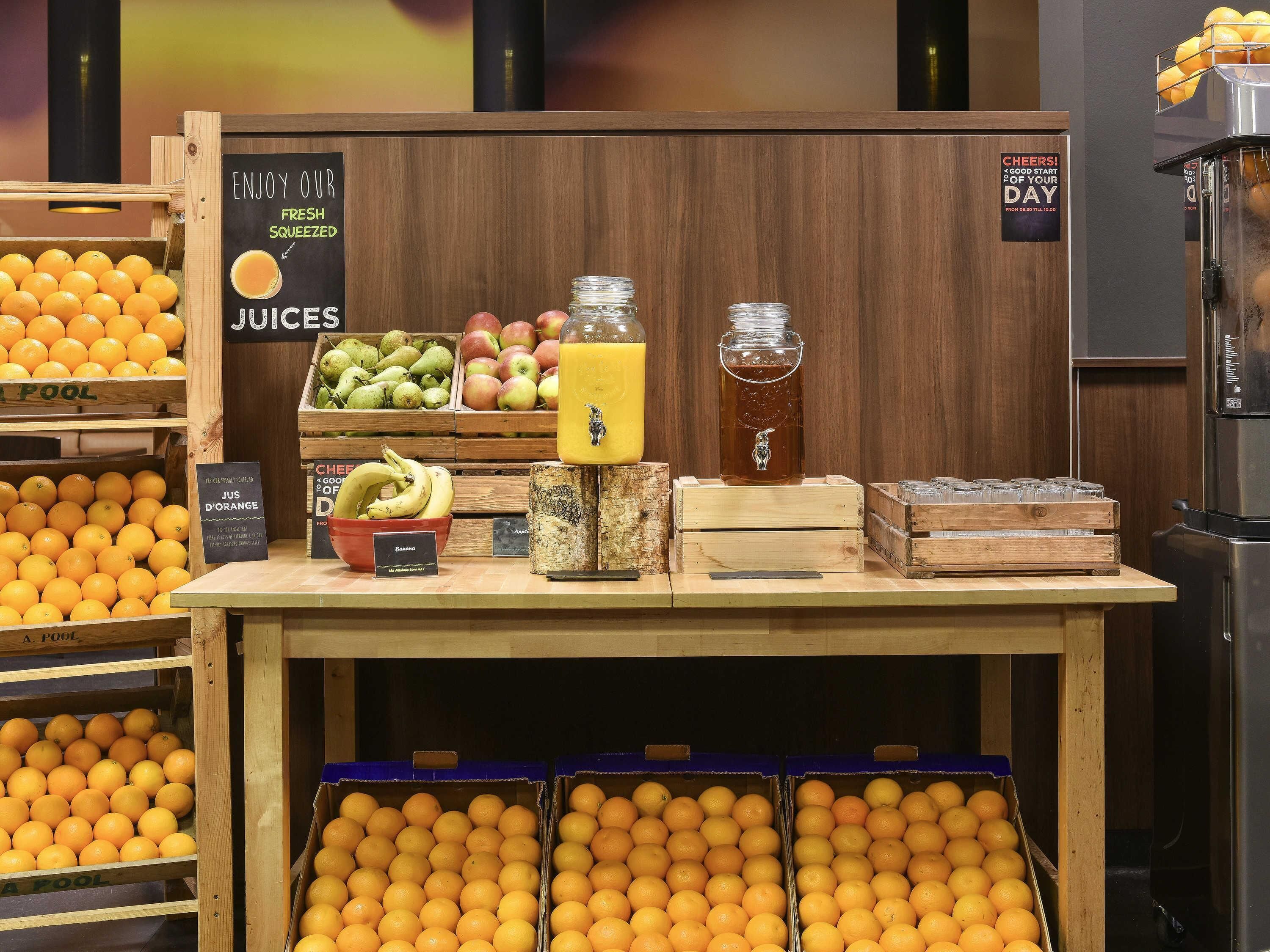 Espaço com sucos de frutas espremidos na hora, diversas frutas e um aviso sobre um ótimo começo de dia.