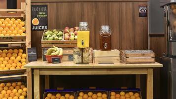 Espaço com sucos de frutas espremidos na hora, diversas frutas e um aviso sobre um ótimo começo de dia.