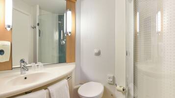 A bathroom with a sink, mirror, toilet, and shower.