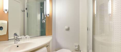 A bathroom with a sink, mirror, toilet, and shower.