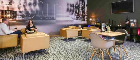 Un área de estar moderna con sofás, una mesa de centro y una barra con botellas.