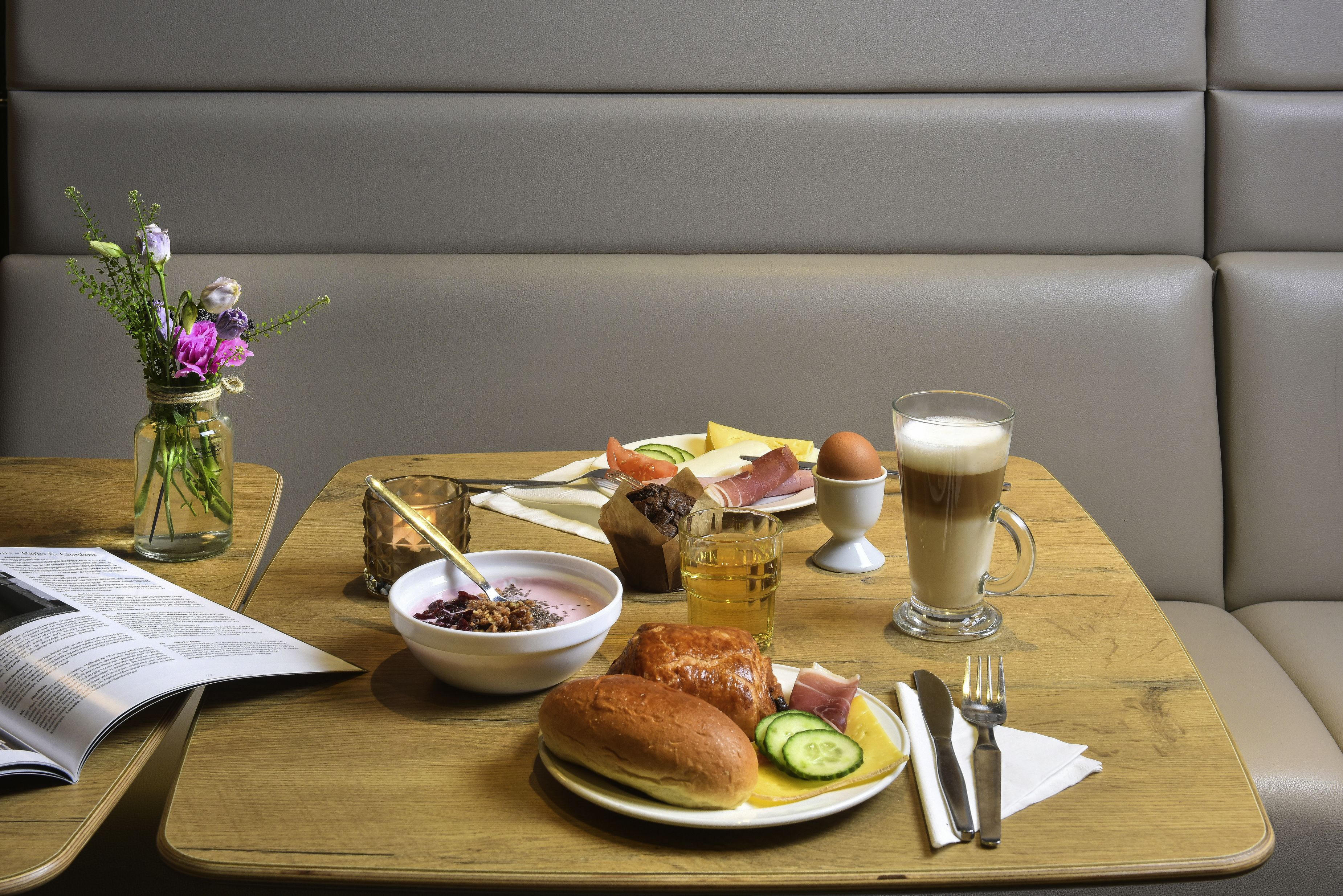 Une table à manger, dressée avec un repas comprenant du pain, des œufs et une boisson, est placée sur une table en bois dans un coin repas.