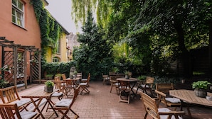 An outdoor patio with wooden furniture and potted plants. - Rinno hotel (Vilnius)