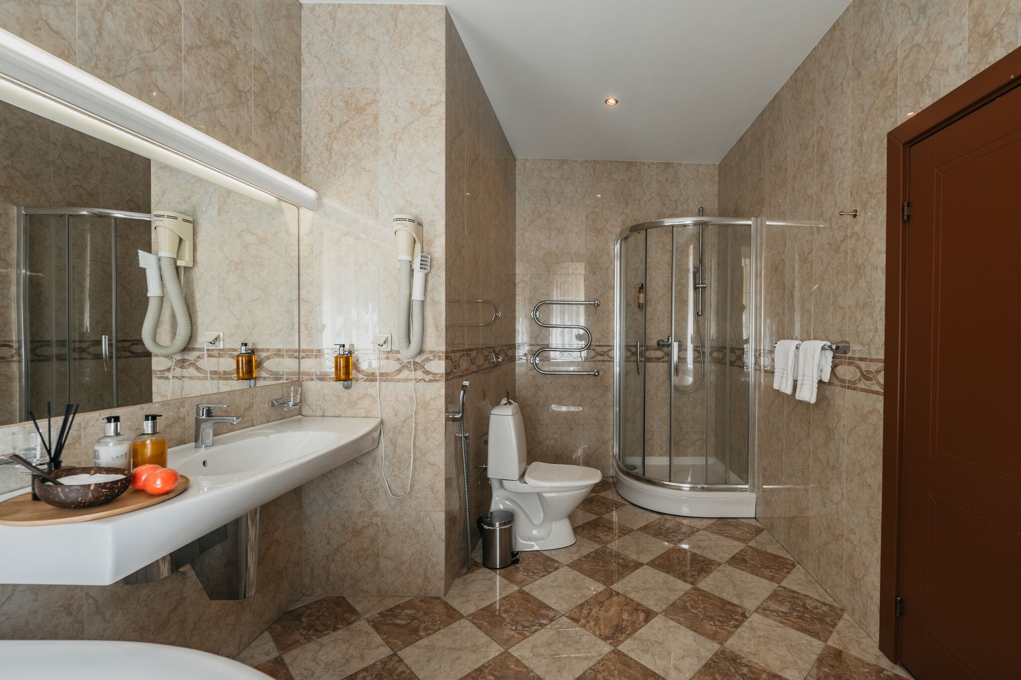 Een moderne badkamer met een wastafel, toilet en een douchecabine met glazen wanden.