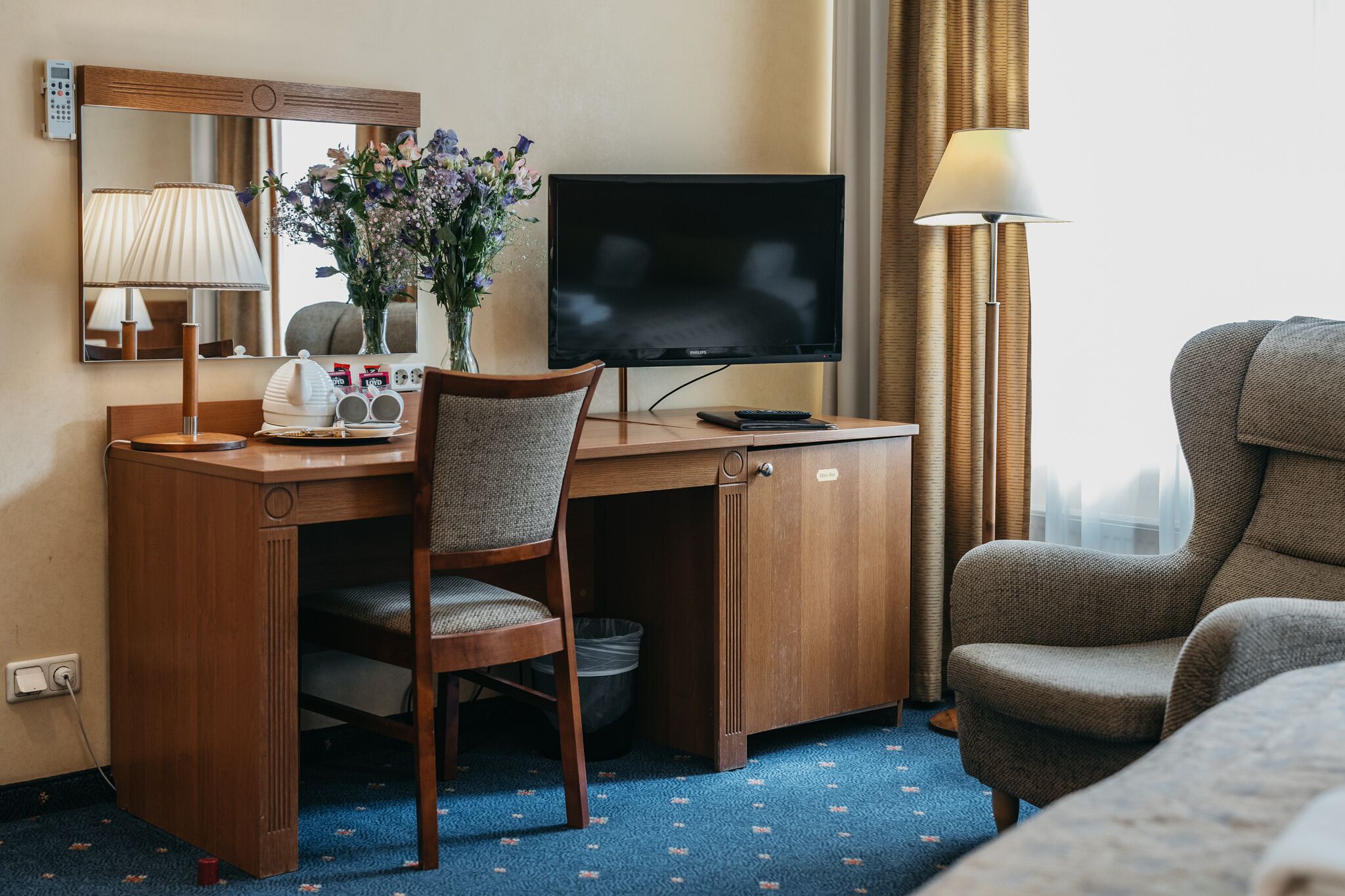 Een hotelkamer met een houten bureau, een televisie, een stoel en een bed.