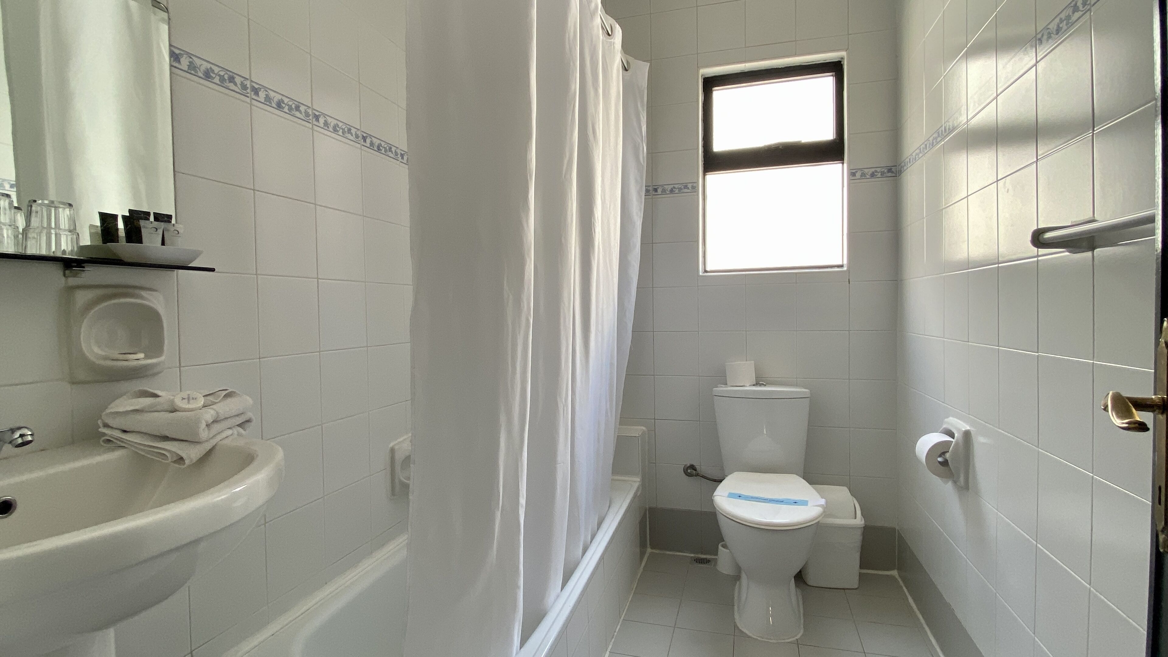 A small, clean bathroom with a toilet, sink, and shower.