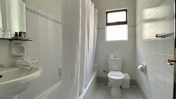 Un baño pequeño y limpio con inodoro, lavamanos y ducha.