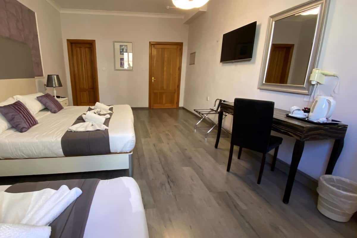 Hotellihuone, jossa on sänky, työpöytä, tuoli, peili ja roskakori.