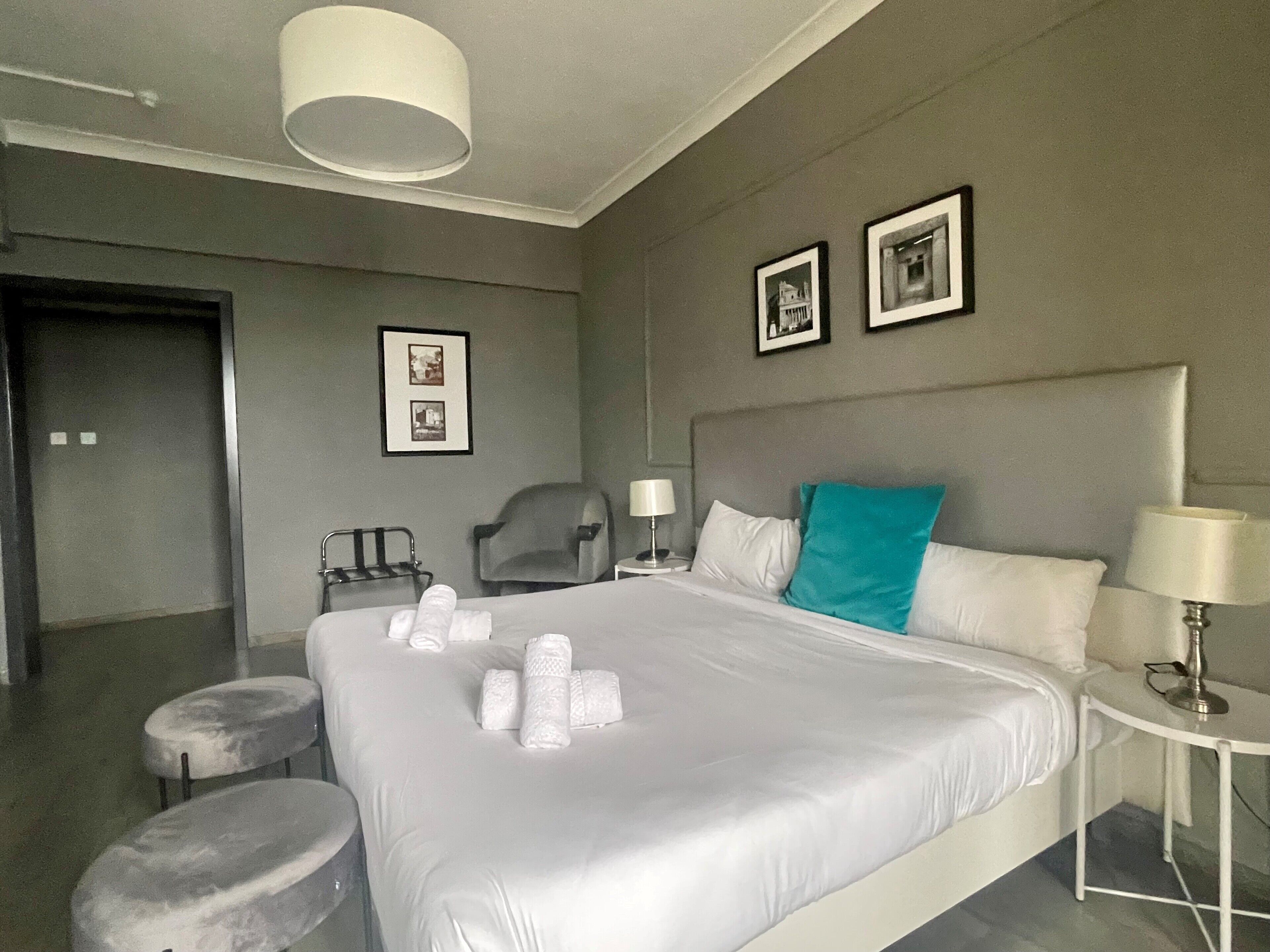 Une chambre d’hôtel avec un grand lit, deux tables de chevet, une chaise, un bureau et une lampe.