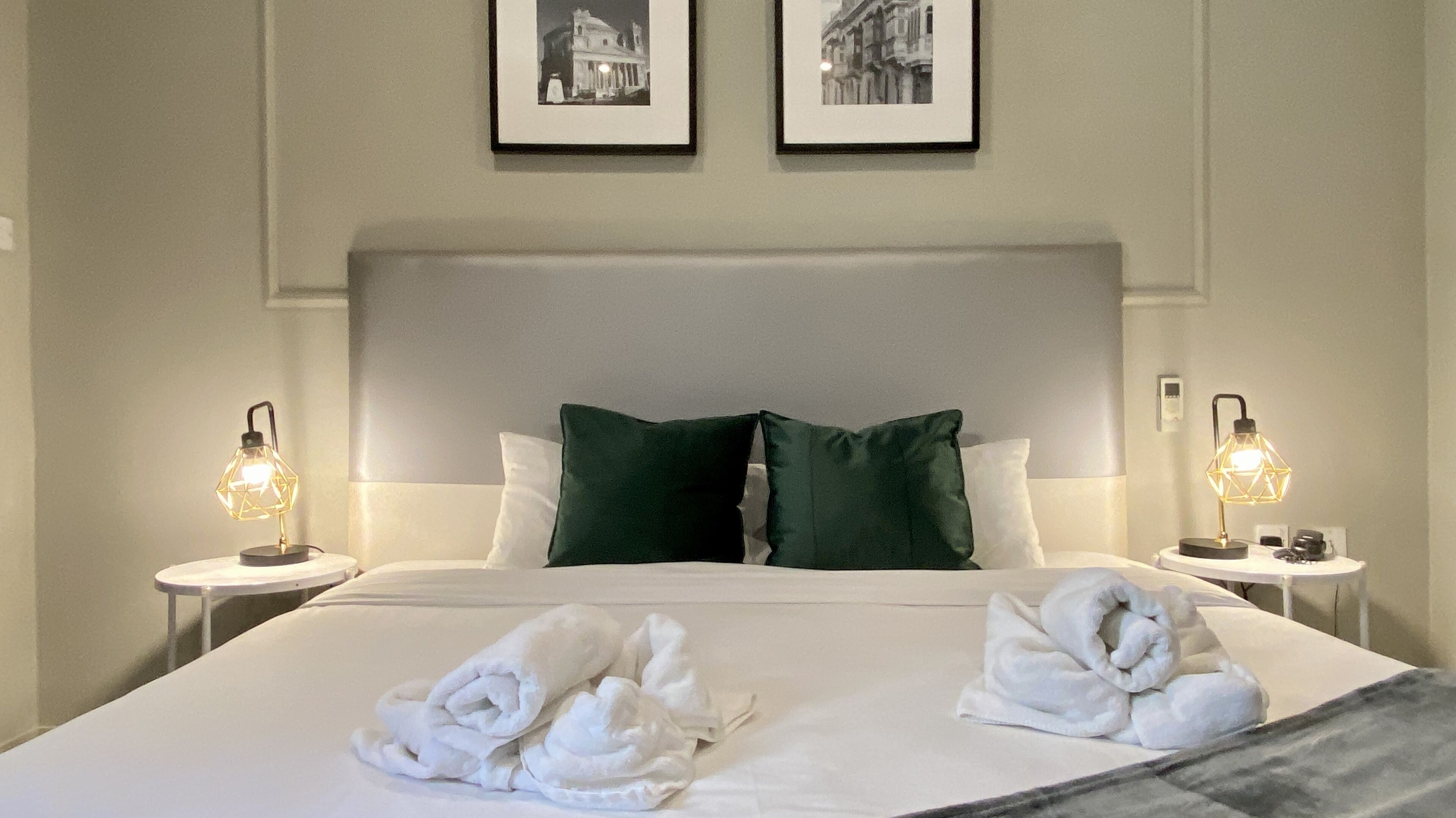 Ein Hotelzimmer mit einem großen Bett, zwei Kissen, zwei Nachttischlampen und zwei Handtüchern auf dem Bett.
