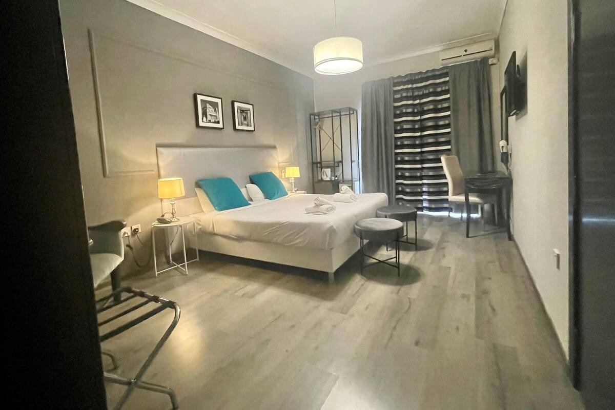Moderni hotellihuone, jossa on suuri sänky, kaksi yöpöytää, työpöytä ja tuoli.