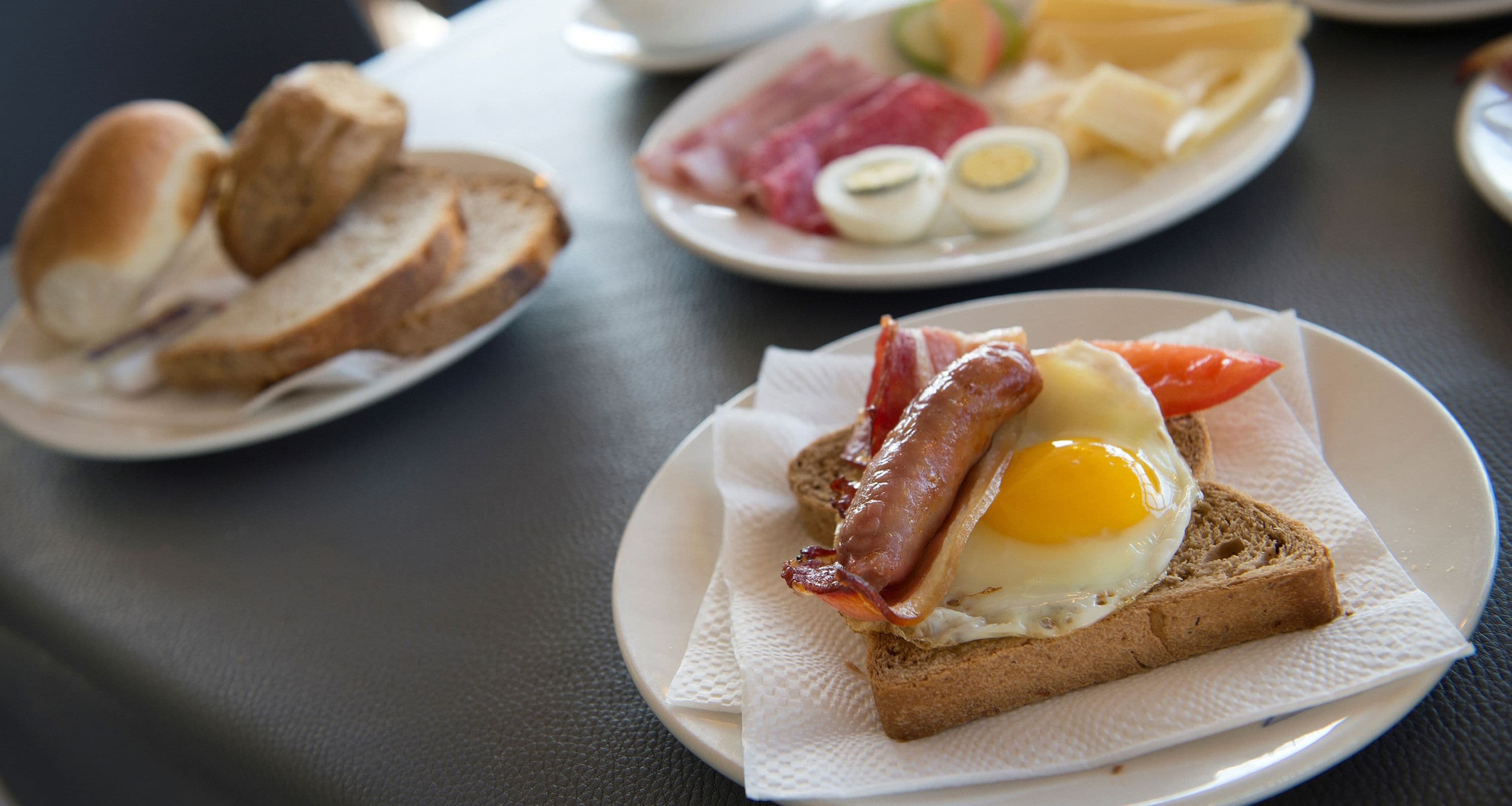 A breakfast plate with toast, bacon, egg, and tomato.
