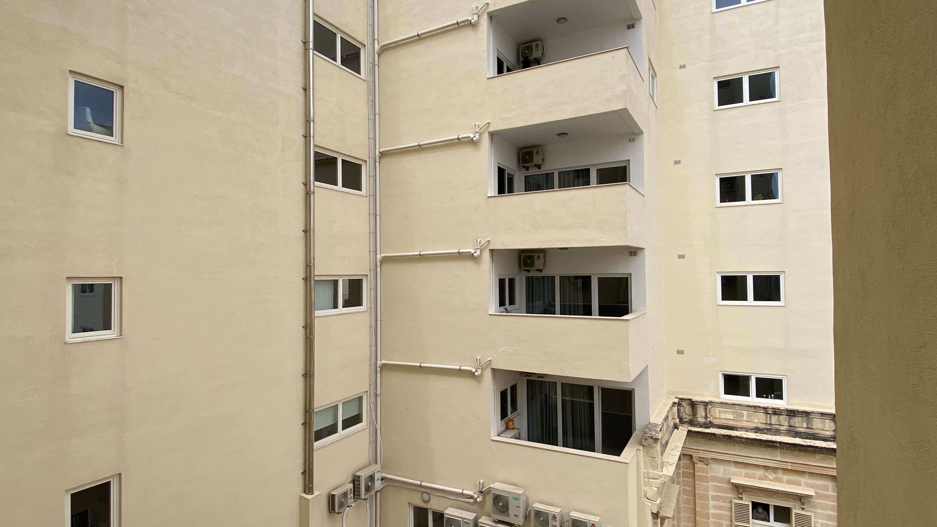 A multi-story building with several balconies and air conditioning units.