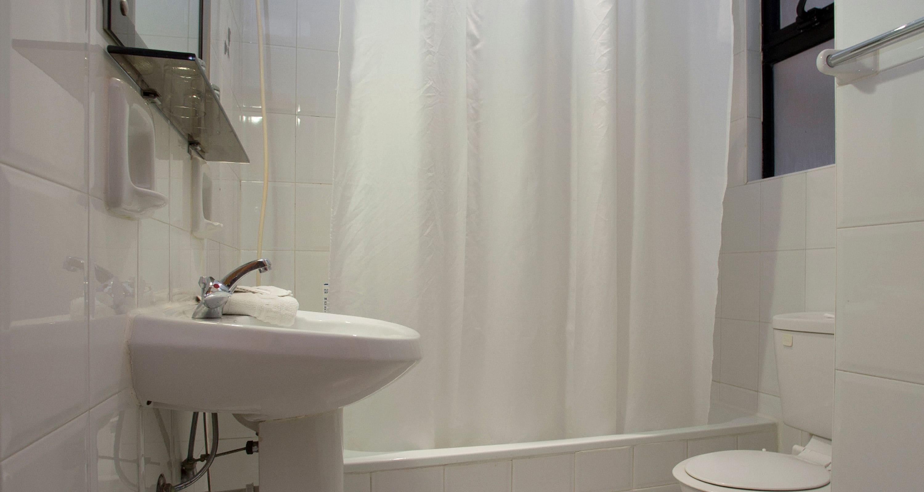 A bathroom with a white sink, a shower curtain, and a toilet.