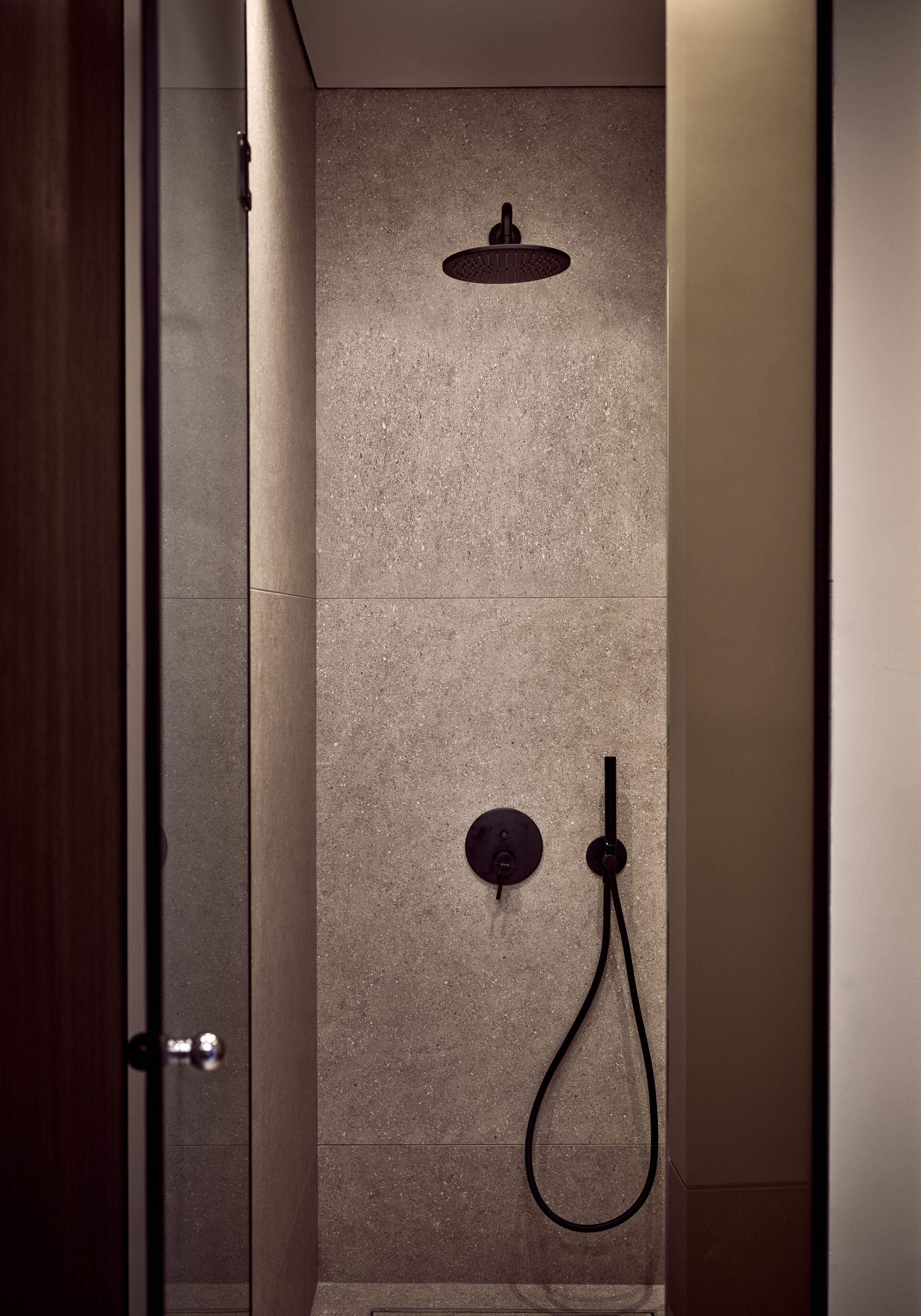 Ducha moderna con cabezal de ducha de mano y grifo empotrado en la pared.