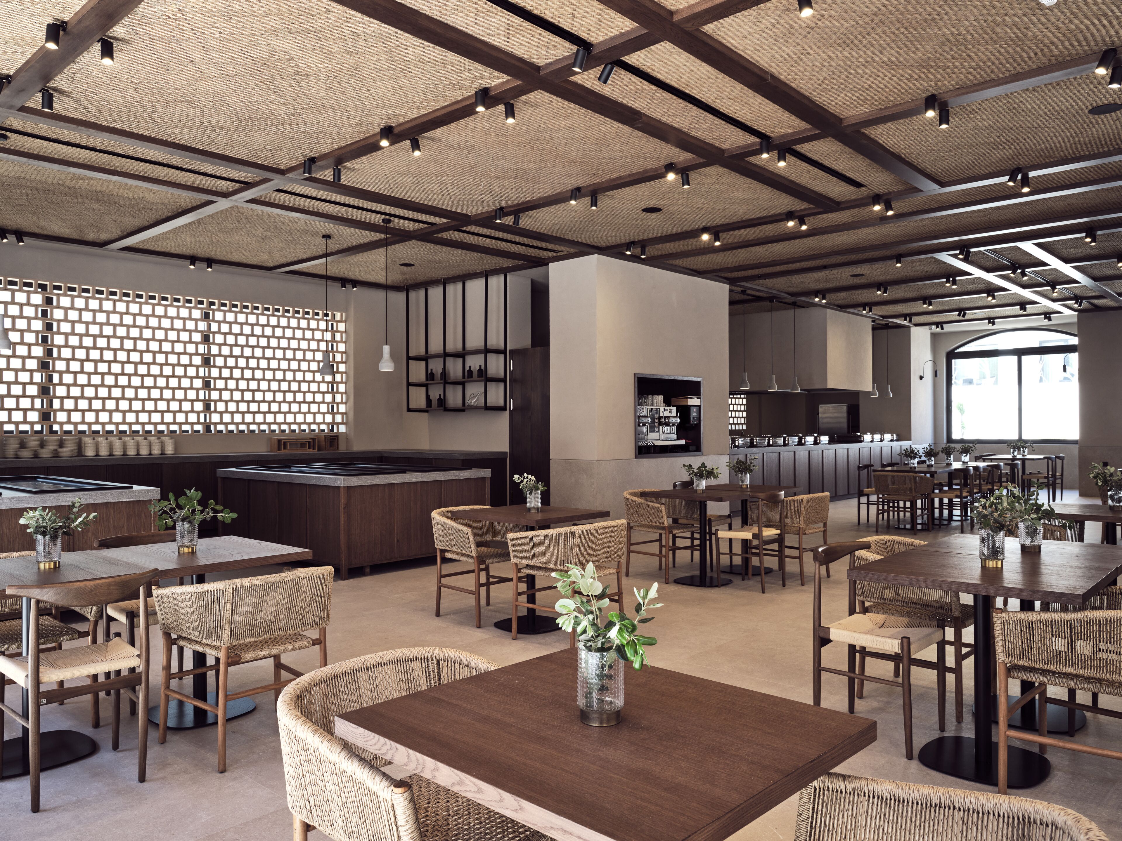 A spacious restaurant with high ceilings, exposed beams, and a variety of seating arrangements including tables and chairs.