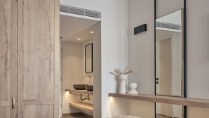 Un dormitorio moderno con un armario de madera, una mesita de noche con un florero y un espejo grande.