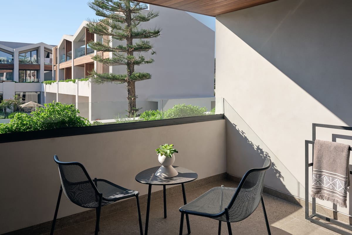 En balkon med to stole, et lille bord og en potteplante.