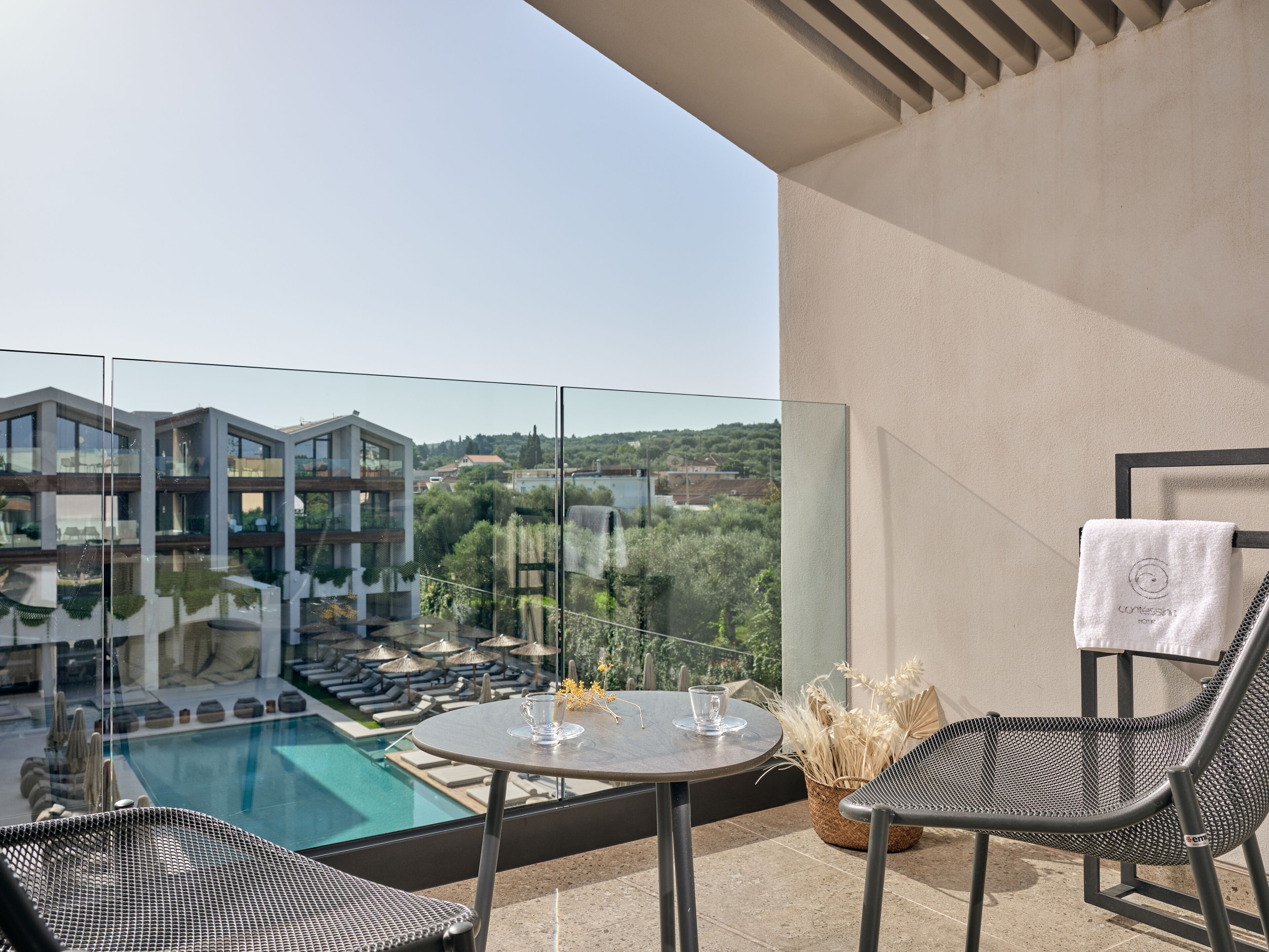 Un balcone con piscina, poltrone da relax e un tavolo con un bicchiere.
