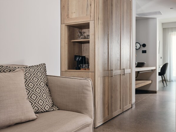 Una sala moderna con un sofá color beige, cojines estampados y un armario de madera con estantes.