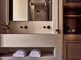 Un bagno con lavandino, spazio per gli asciugamani, uno specchio e una macchina da caffè.