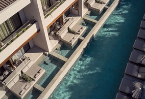 Un hotel moderno con area piscina sul tetto, con diverse poltrone relax e una piscina di colore blu intenso.