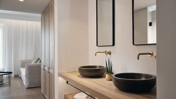 Un bagno moderno con un mobile bagno in legno, due lavabi capienti, una piccola pianta e uno specchio.