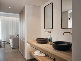 Un bagno moderno con un mobile bagno in legno, due lavabi capienti, una piccola pianta e uno specchio.