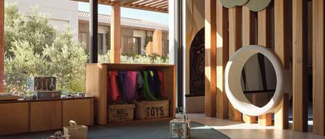 A modern interior with a wooden play area, a large window, and a circular wall decoration.