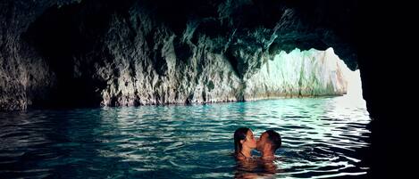 Un couple s’embrasse dans une grotte aux parois rocheuses, où l’eau s’écoule.