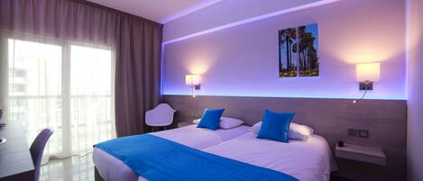A modern hotel room with a large bed, two bedside tables, a desk, and a chair.
