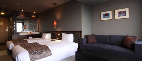 A hotel room with two beds, a sofa, a large mirror, and framed artwork on the wall.