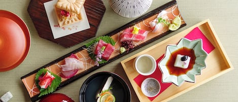 Un pasto tradizionale giapponese con sashimi, una piccola torta e una ciotola di zuppa.